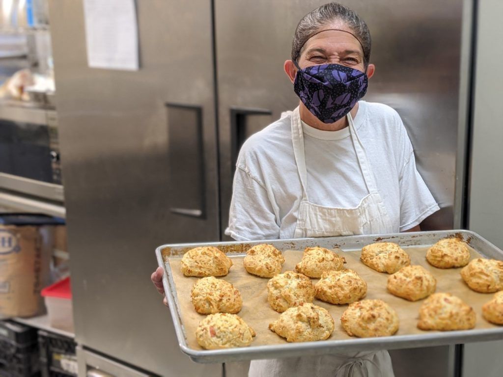 woman holding pan of baking scones in commercial kitchen