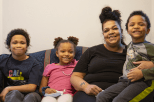 smiling mom with smiling kids sitting on couch